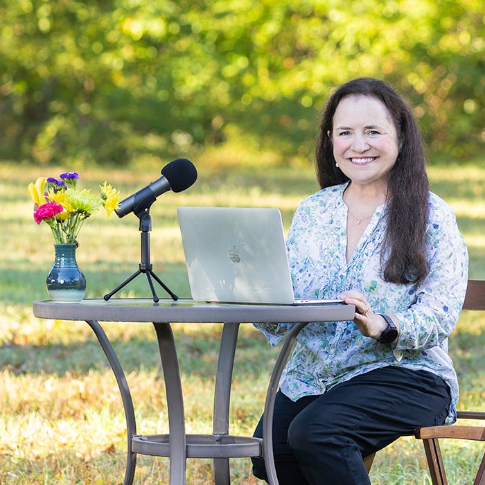 Maria T. Finch recording the Silence the Mindcluck® Podcast outdoors with a microphone and laptop.